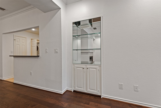 corridor featuring stacked washer and dryer, dark hardwood / wood-style flooring, and ornamental molding