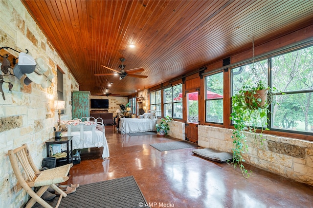 unfurnished sunroom featuring a wealth of natural light, ceiling fan, and wooden ceiling