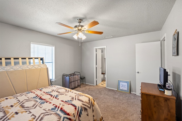 carpeted bedroom featuring connected bathroom, a textured ceiling, and ceiling fan