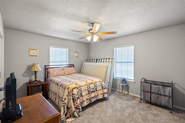 bedroom with ceiling fan, multiple windows, light carpet, and a textured ceiling