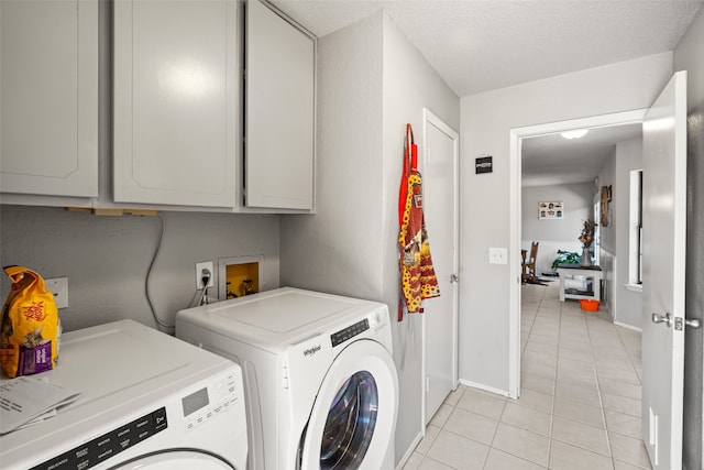 laundry room featuring a textured ceiling, separate washer and dryer, cabinets, and light tile patterned floors