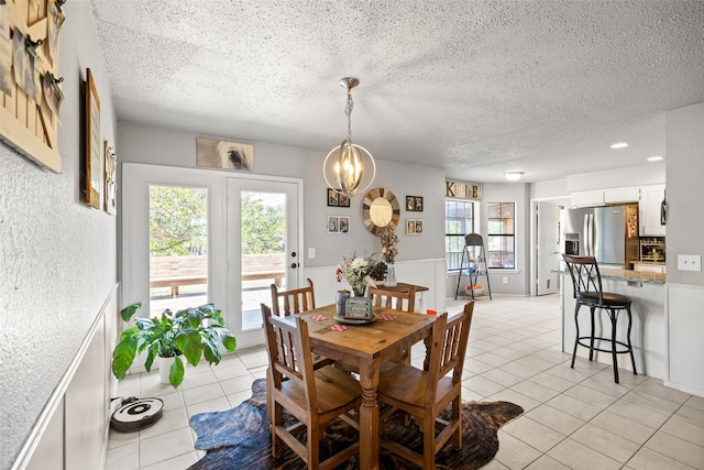 dining room with a textured ceiling, light tile patterned floors, and a healthy amount of sunlight