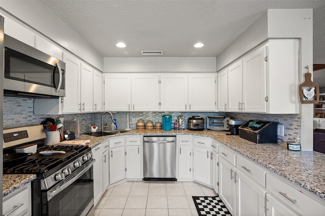 kitchen featuring white cabinetry, stainless steel appliances, a textured ceiling, and sink