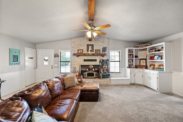 carpeted living room with a brick fireplace, a textured ceiling, ceiling fan, and vaulted ceiling