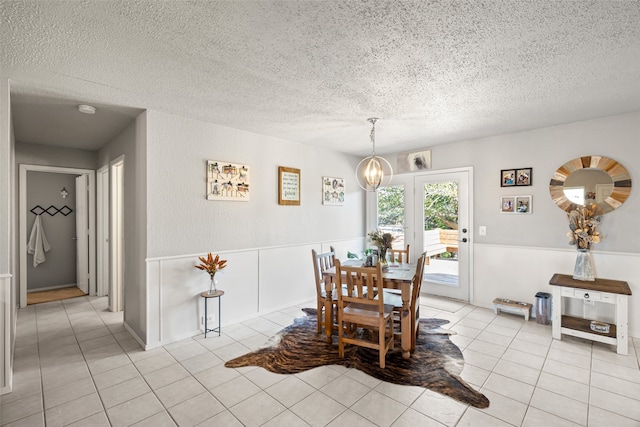 dining space with a chandelier, a textured ceiling, and light tile patterned flooring