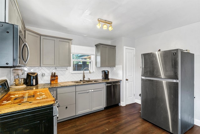 kitchen with stainless steel appliances, dark wood-type flooring, sink, gray cabinets, and backsplash