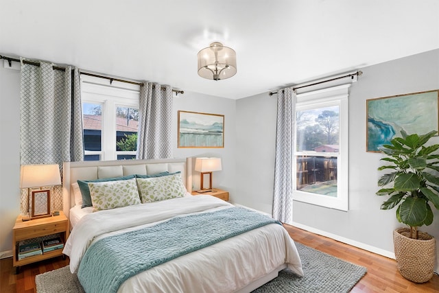 bedroom featuring hardwood / wood-style flooring, a notable chandelier, and multiple windows