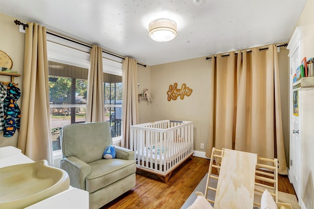 bedroom with a nursery area and hardwood / wood-style flooring