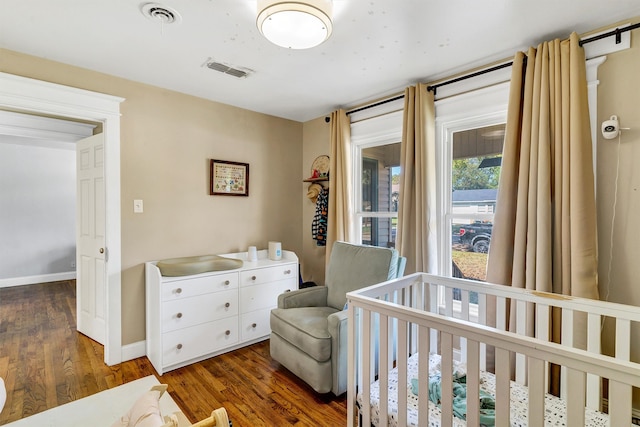 bedroom with dark hardwood / wood-style floors and a nursery area