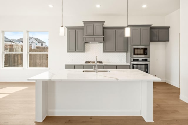 kitchen featuring light stone counters, light wood finished floors, stainless steel oven, and built in microwave