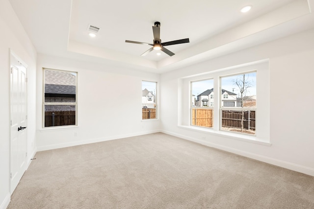 carpeted empty room with baseboards, visible vents, a tray ceiling, and recessed lighting