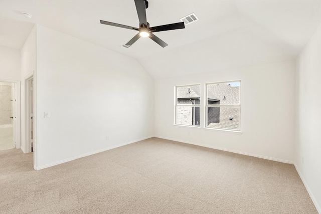 spare room featuring baseboards, visible vents, a ceiling fan, light colored carpet, and vaulted ceiling