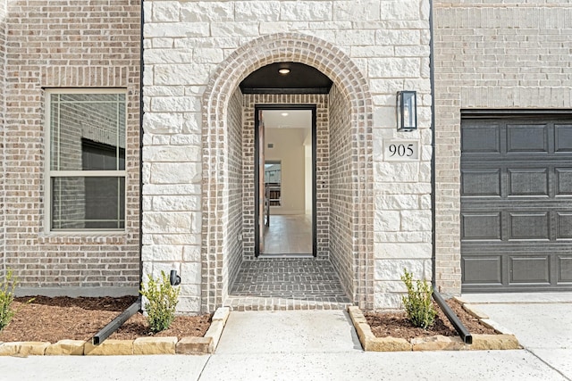 property entrance featuring a garage and brick siding