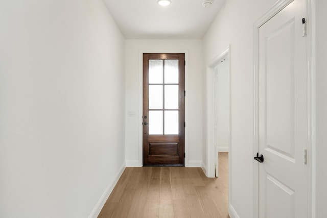 doorway featuring light wood-style flooring and baseboards