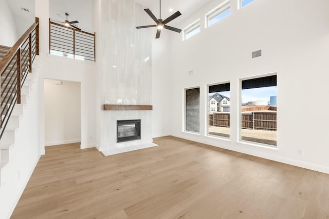 unfurnished living room featuring a large fireplace, ceiling fan, visible vents, and wood finished floors