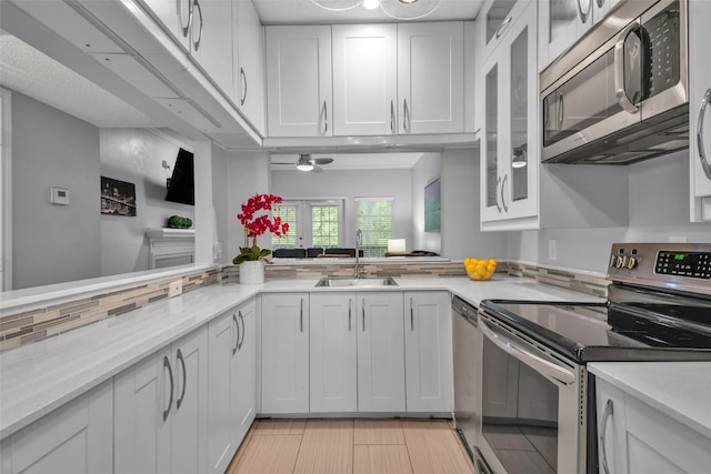 kitchen featuring white cabinets, sink, ceiling fan, kitchen peninsula, and stainless steel appliances