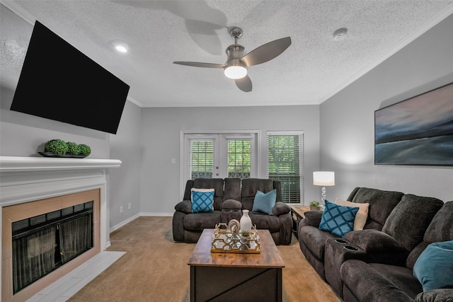 living room with light carpet, ceiling fan, ornamental molding, a textured ceiling, and a tiled fireplace