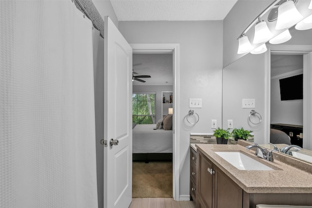 bathroom with ceiling fan, wood-type flooring, a textured ceiling, and vanity