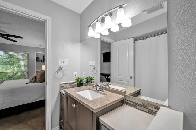 bathroom with ceiling fan, vanity, and a textured ceiling