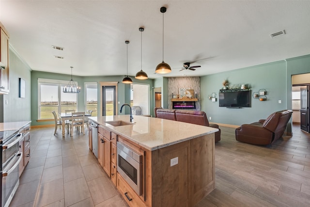 kitchen featuring a wealth of natural light, sink, decorative light fixtures, and an island with sink