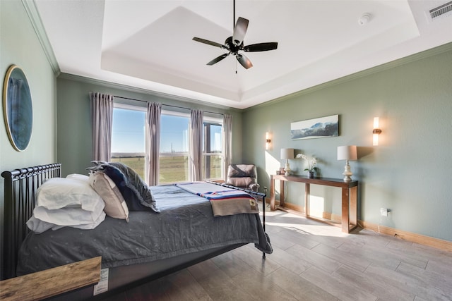 bedroom with ceiling fan, a raised ceiling, light wood-type flooring, and crown molding