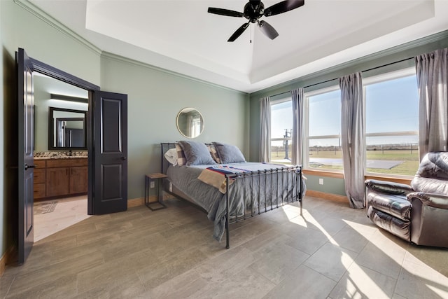 bedroom with ensuite bathroom, ceiling fan, and a tray ceiling