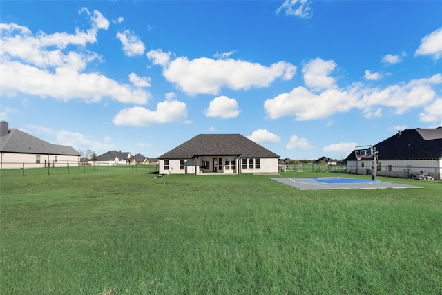 rear view of house with basketball court and a lawn