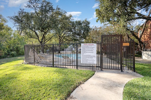 view of gate featuring a lawn and a community pool