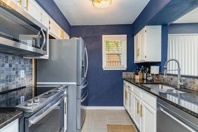 kitchen featuring backsplash, dark stone counters, white cabinets, sink, and stainless steel appliances