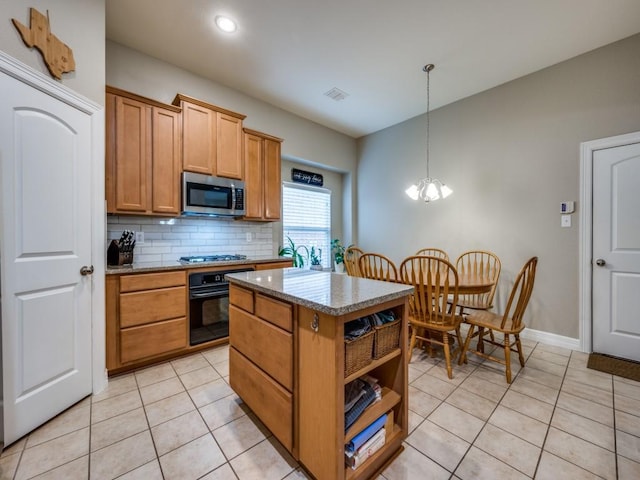 kitchen with light stone countertops, hanging light fixtures, stainless steel appliances, a notable chandelier, and a kitchen island