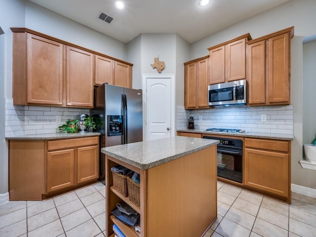 kitchen featuring light tile patterned floors, tasteful backsplash, light stone counters, a kitchen island, and appliances with stainless steel finishes