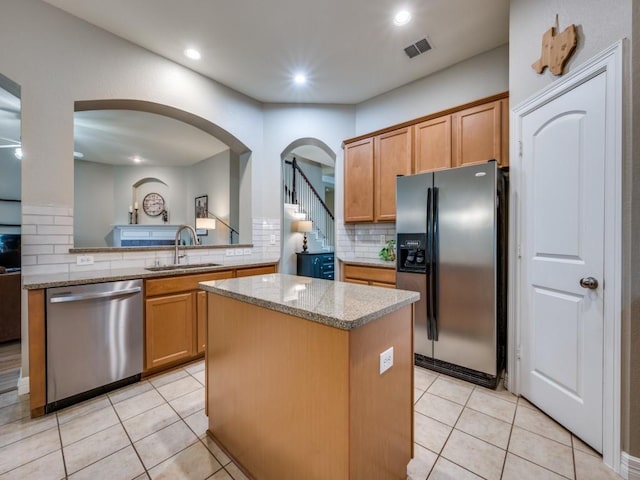 kitchen with kitchen peninsula, backsplash, stainless steel appliances, sink, and a center island