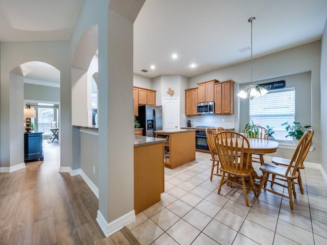 kitchen featuring a kitchen island, stainless steel appliances, a wealth of natural light, and light hardwood / wood-style flooring