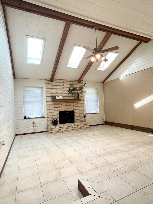 unfurnished living room featuring vaulted ceiling with skylight, a wealth of natural light, light tile patterned floors, and ceiling fan