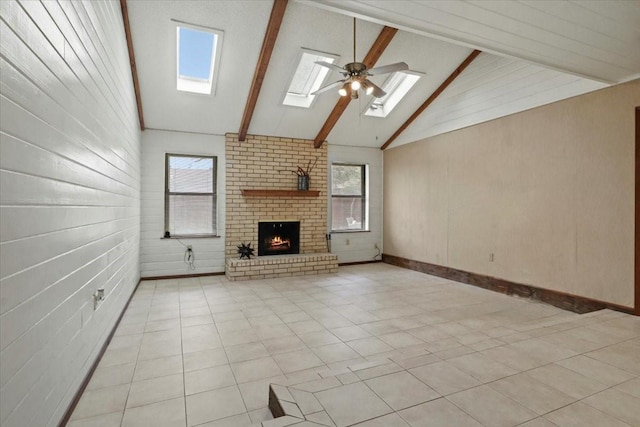 unfurnished living room featuring light tile patterned floors, beam ceiling, a skylight, high vaulted ceiling, and a fireplace