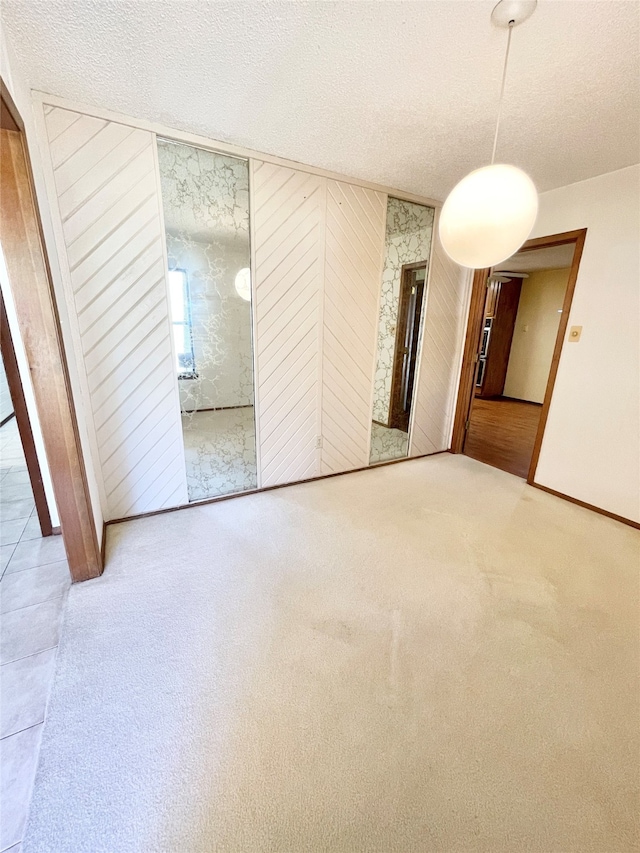 unfurnished room with wood walls, a textured ceiling, and carpet floors