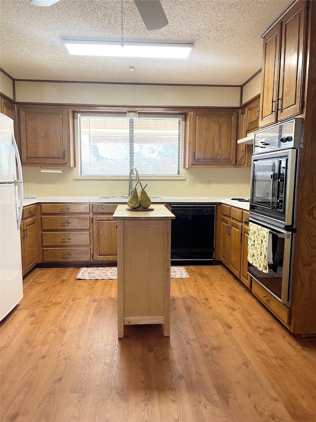 kitchen with double wall oven, sink, white refrigerator, light wood-type flooring, and black dishwasher