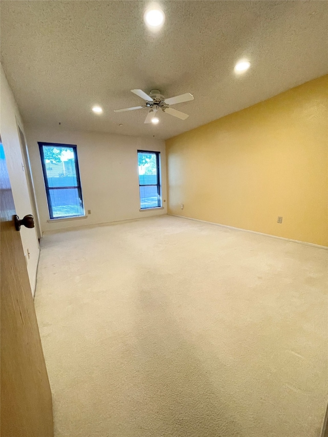 carpeted empty room featuring ceiling fan and a textured ceiling