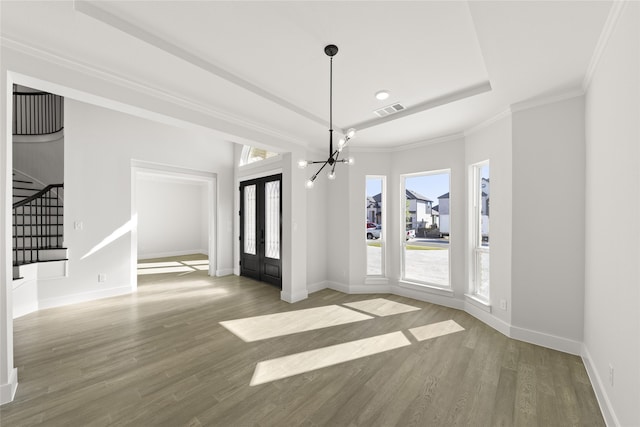 entrance foyer featuring a chandelier, wood-type flooring, a raised ceiling, and ornamental molding