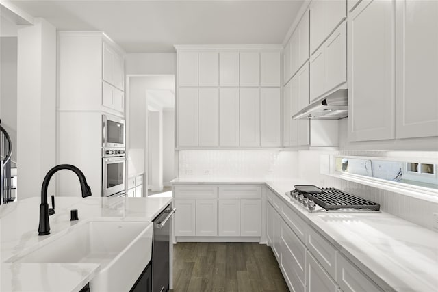 kitchen featuring light stone countertops, white cabinetry, sink, dark wood-type flooring, and appliances with stainless steel finishes