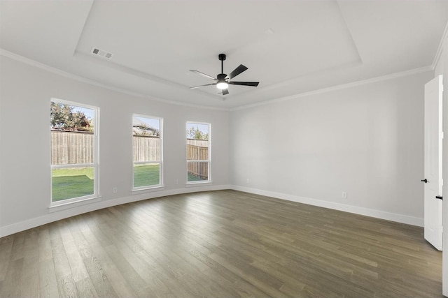 unfurnished room featuring dark wood-style floors, a raised ceiling, visible vents, ornamental molding, and baseboards