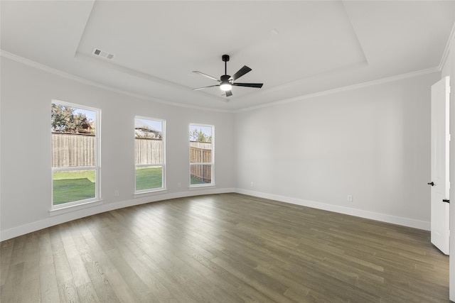 empty room featuring ceiling fan, dark hardwood / wood-style flooring, a raised ceiling, and ornamental molding