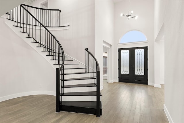 entrance foyer featuring a chandelier, wood finished floors, baseboards, french doors, and stairway