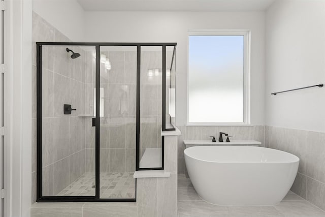 full bath featuring a freestanding bath, wainscoting, a shower stall, and tile walls
