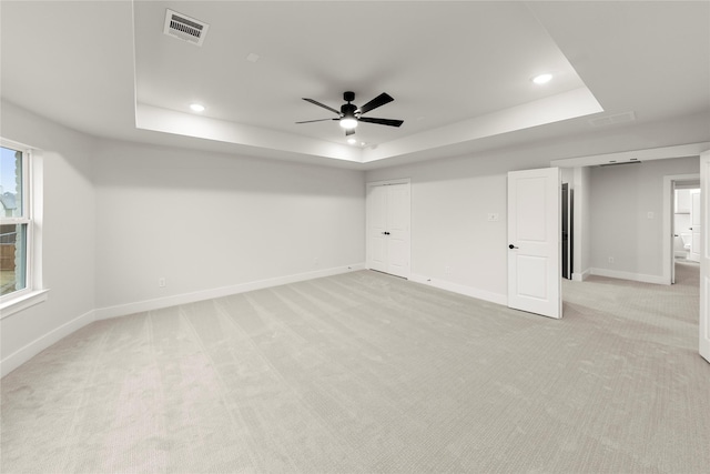 interior space featuring light colored carpet, a raised ceiling, visible vents, and baseboards