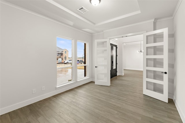 spare room with a raised ceiling, baseboards, and wood finished floors