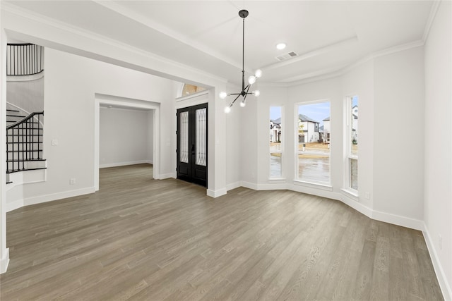 unfurnished dining area featuring baseboards, ornamental molding, wood finished floors, stairs, and a chandelier