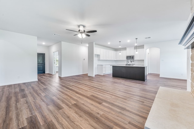 unfurnished living room featuring light wood-style floors, arched walkways, recessed lighting, and ceiling fan