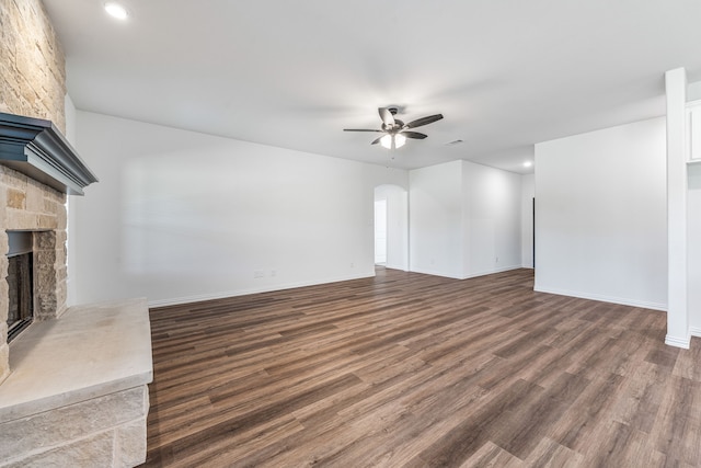 unfurnished living room featuring dark wood-style floors, arched walkways, recessed lighting, ceiling fan, and a fireplace