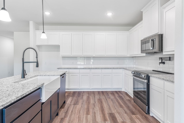 kitchen featuring white cabinets, stainless steel appliances, a sink, tasteful backsplash, and wood finished floors